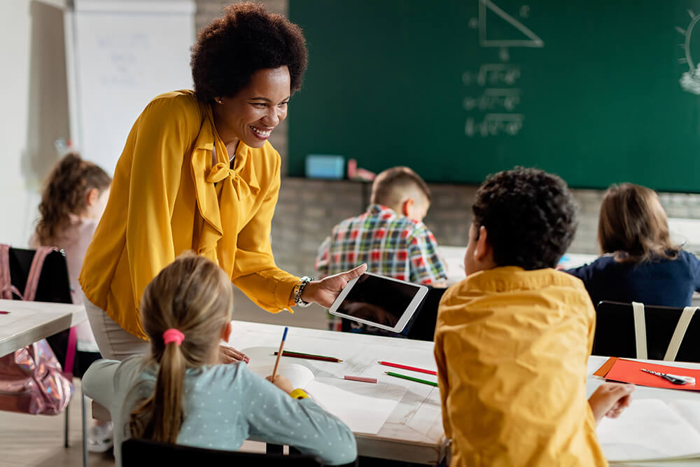Teacher and elementary students using digital tablet in the classroom